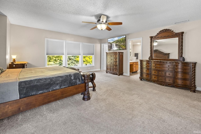 bedroom featuring a textured ceiling, ensuite bathroom, light colored carpet, and ceiling fan