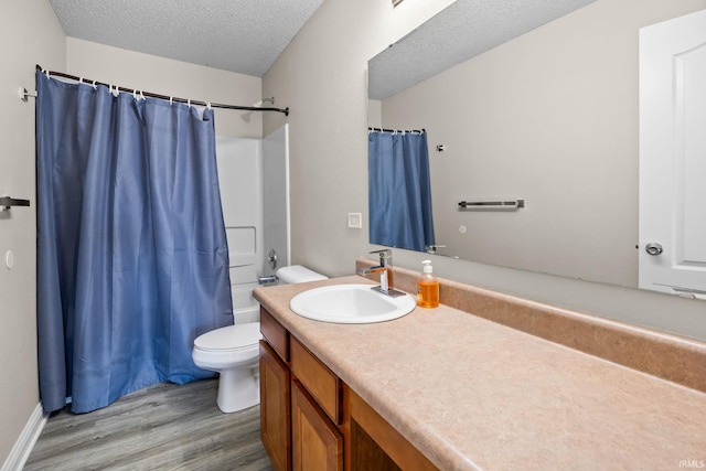 full bathroom featuring hardwood / wood-style floors, a textured ceiling, toilet, vanity, and shower / tub combo with curtain