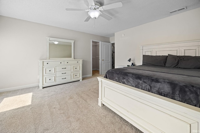 carpeted bedroom featuring a spacious closet, a textured ceiling, and ceiling fan