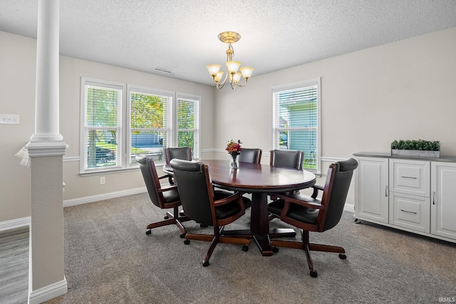 carpeted dining space with a chandelier, decorative columns, a textured ceiling, and plenty of natural light