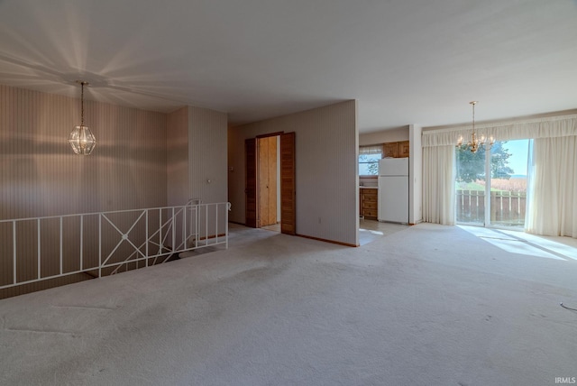 carpeted spare room with an inviting chandelier