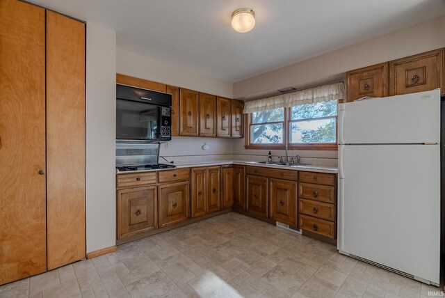 kitchen with stainless steel gas stovetop, sink, and white refrigerator