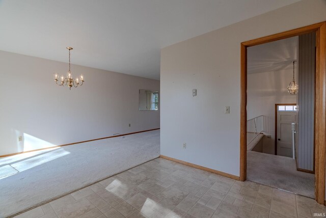 carpeted empty room with a notable chandelier