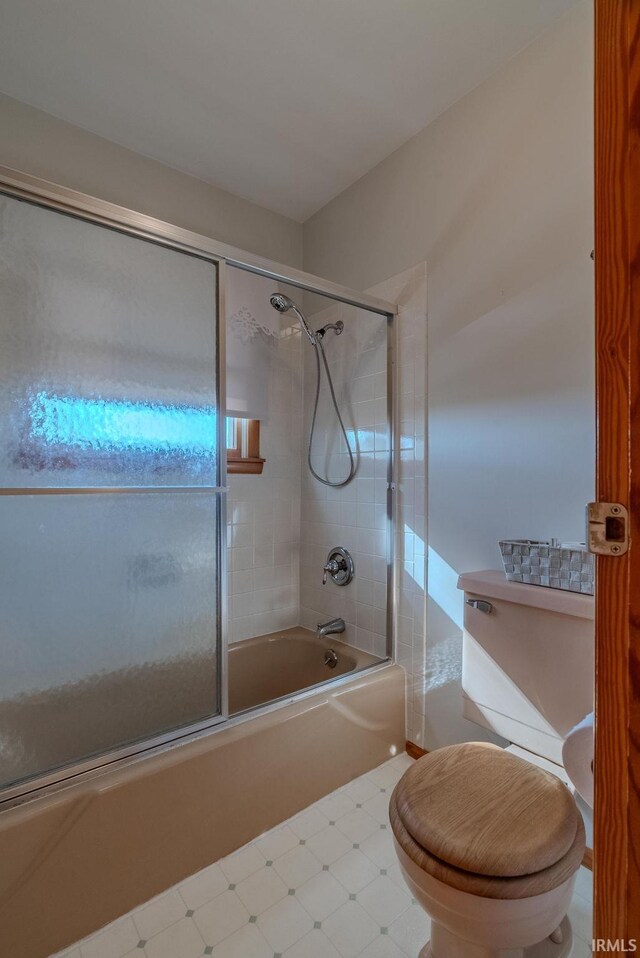 bathroom featuring bath / shower combo with glass door and toilet