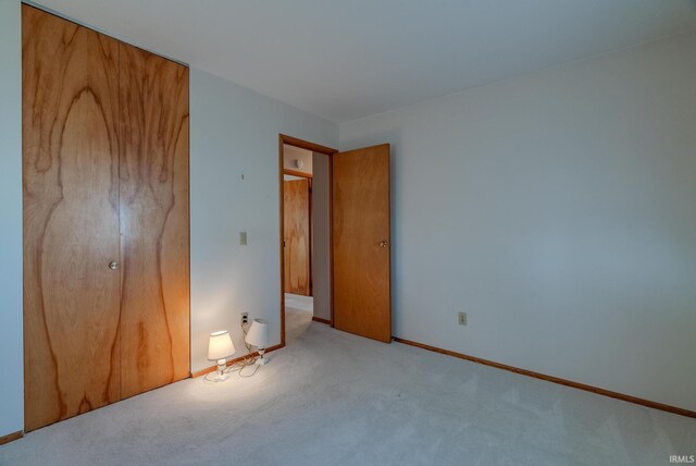unfurnished bedroom featuring a closet and light colored carpet