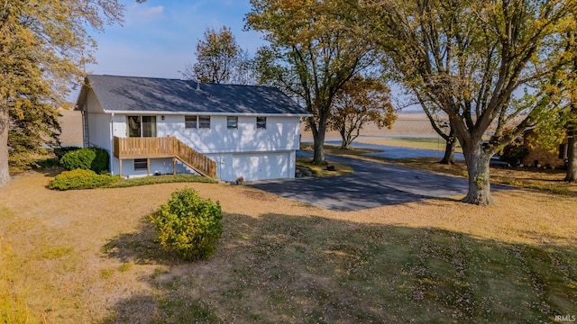 back of property with a porch, a garage, and a water view