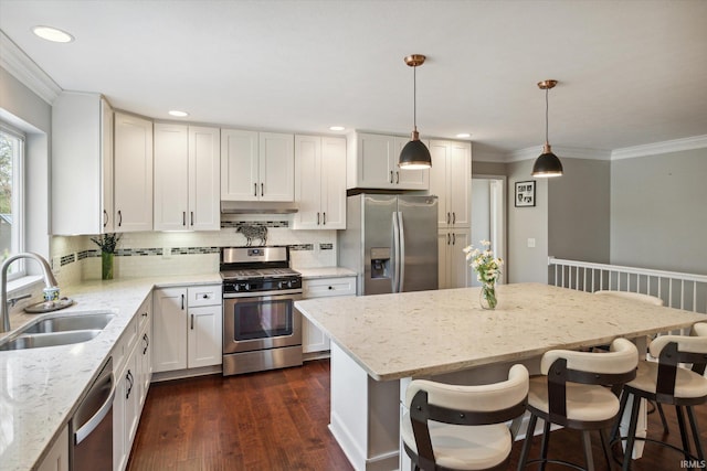 kitchen with dark wood-type flooring, stainless steel appliances, sink, pendant lighting, and white cabinets