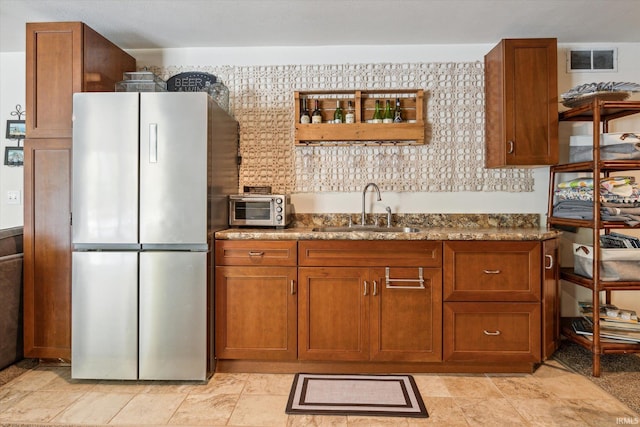 kitchen with sink, stainless steel fridge, and dark stone counters