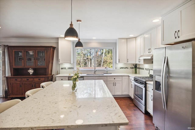 kitchen with appliances with stainless steel finishes, sink, white cabinetry, pendant lighting, and dark wood-type flooring