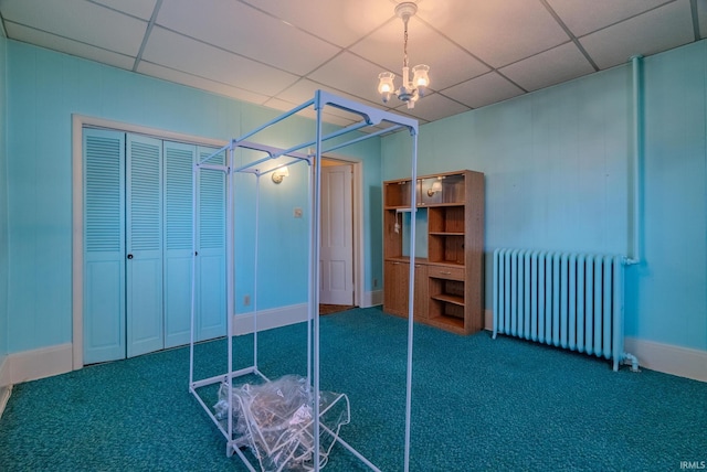 unfurnished bedroom featuring a closet, carpet floors, radiator, and a paneled ceiling