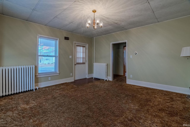 carpeted spare room featuring radiator and an inviting chandelier