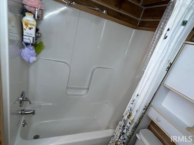 bathroom featuring shower / tub combo and toilet