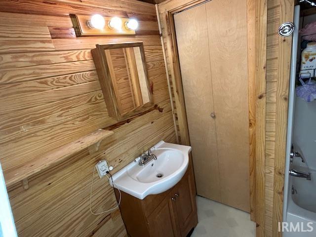 bathroom featuring vanity, wood walls, and a shower