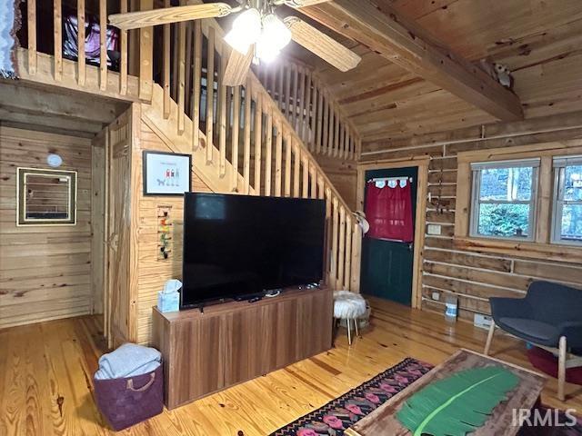 living room featuring wooden walls, hardwood / wood-style flooring, wood ceiling, and vaulted ceiling with beams