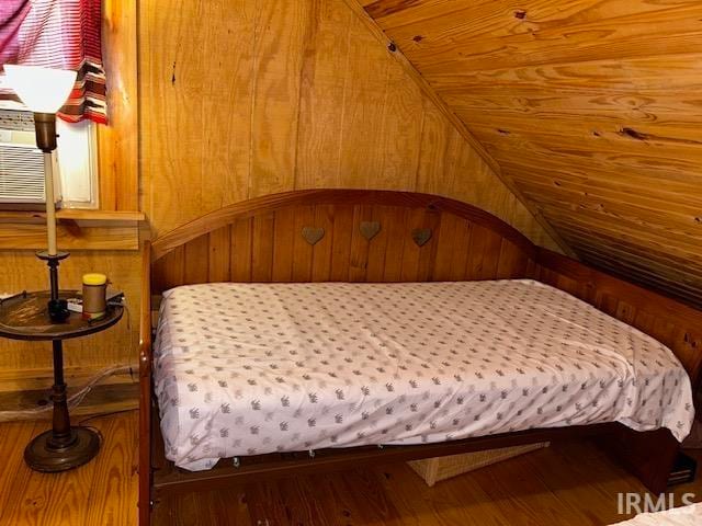 bedroom with hardwood / wood-style flooring and wooden walls