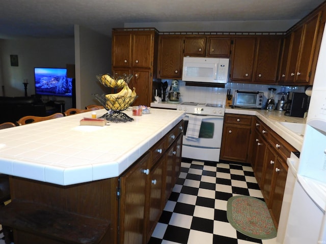 kitchen with tile counters, backsplash, and white appliances