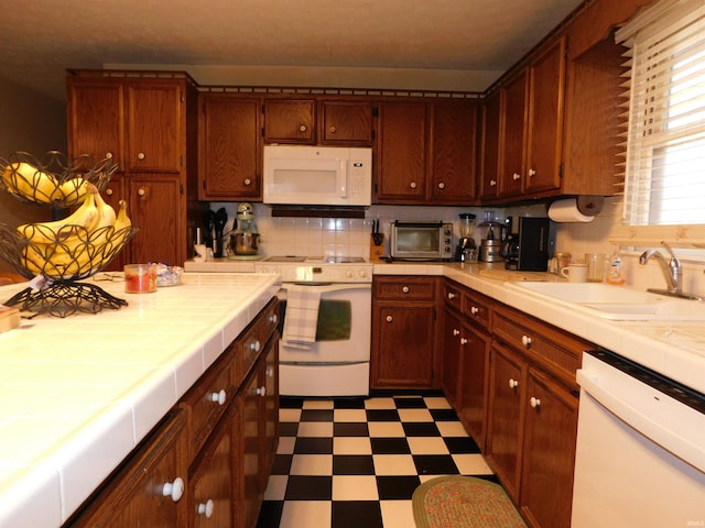 kitchen featuring tile counters, tasteful backsplash, sink, and white appliances