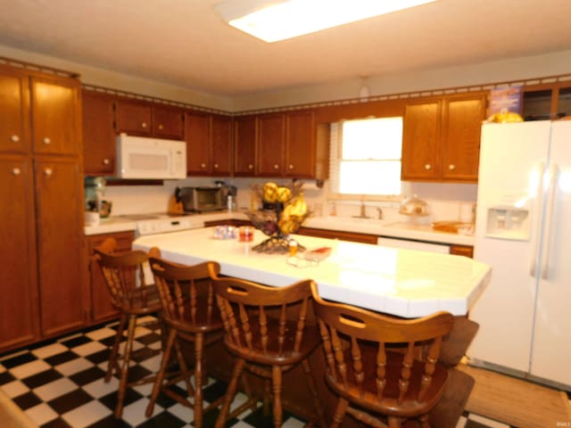 kitchen with a kitchen island, a kitchen bar, and white appliances