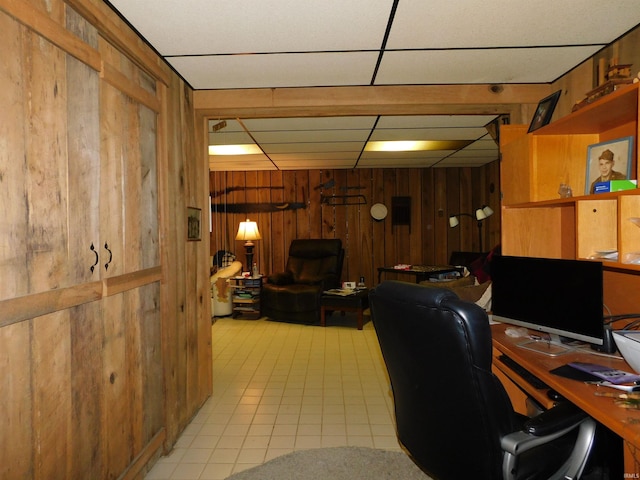 tiled office featuring wood walls and a paneled ceiling