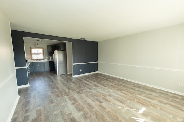 unfurnished living room featuring sink and light wood-type flooring