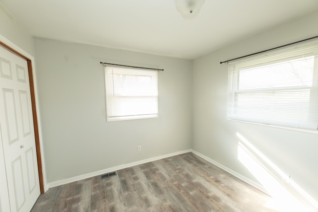 unfurnished bedroom with a closet, multiple windows, and hardwood / wood-style floors