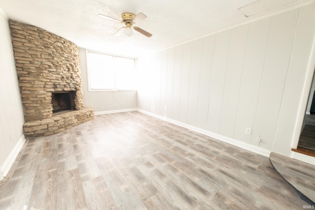 unfurnished living room featuring a fireplace, crown molding, light wood-type flooring, a textured ceiling, and ceiling fan