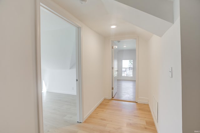 hallway with light hardwood / wood-style floors and lofted ceiling