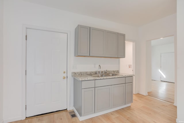 kitchen with light hardwood / wood-style flooring, gray cabinetry, and sink