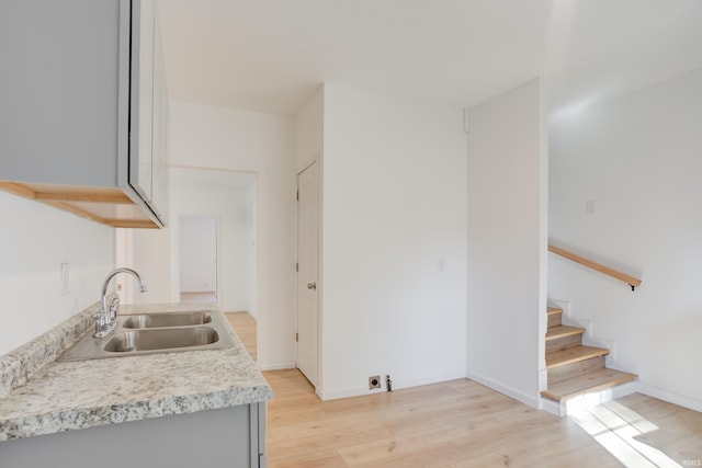 kitchen with gray cabinetry, light hardwood / wood-style floors, and sink