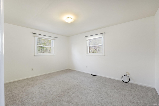 spare room featuring light carpet and plenty of natural light