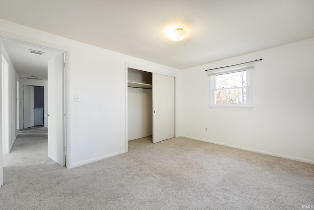 unfurnished bedroom featuring light carpet and a closet