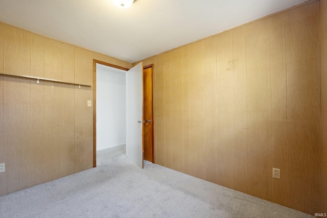 unfurnished bedroom with light carpet and wooden walls