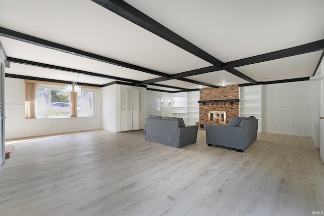 unfurnished living room with beamed ceiling, a brick fireplace, and light hardwood / wood-style floors