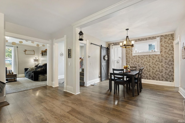 dining area with ornamental molding, a barn door, and dark hardwood / wood-style flooring