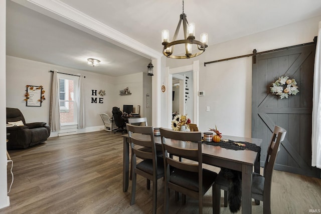 dining area featuring dark hardwood / wood-style floors, a chandelier, and a barn door