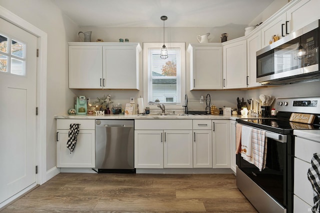 kitchen with hardwood / wood-style flooring, a healthy amount of sunlight, appliances with stainless steel finishes, and white cabinets