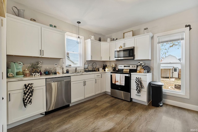 kitchen featuring appliances with stainless steel finishes, hanging light fixtures, dark hardwood / wood-style floors, and white cabinetry