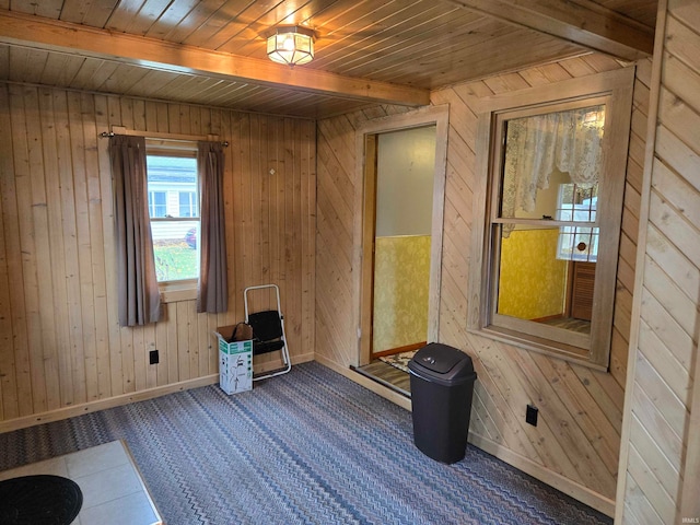 unfurnished room with beamed ceiling, wooden ceiling, and wood walls