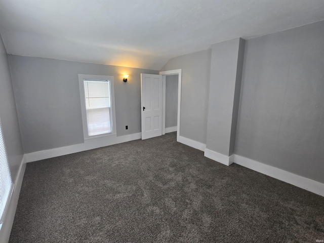 empty room featuring lofted ceiling and dark carpet