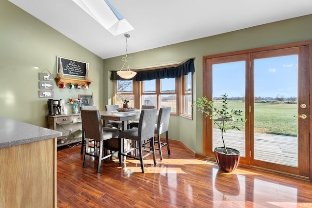 dining area with lofted ceiling with skylight and hardwood / wood-style floors