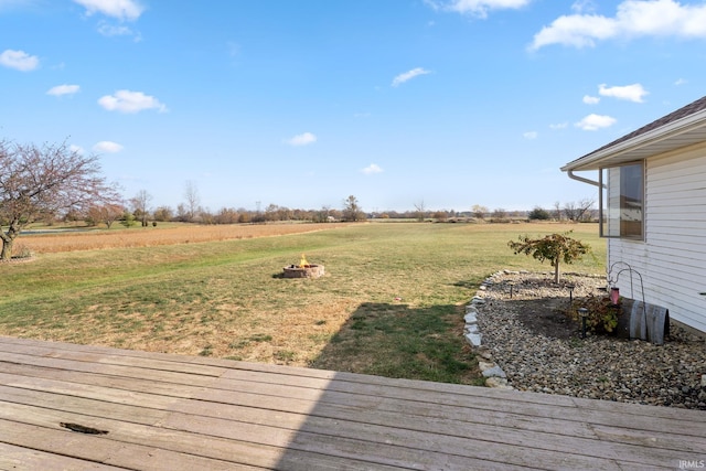 wooden terrace with a yard, an outdoor fire pit, and a rural view