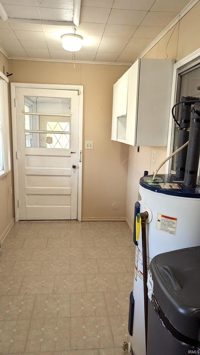 laundry area with electric water heater and cabinets