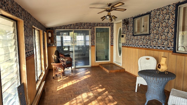 interior space with wooden walls, vaulted ceiling, dark parquet floors, and ceiling fan