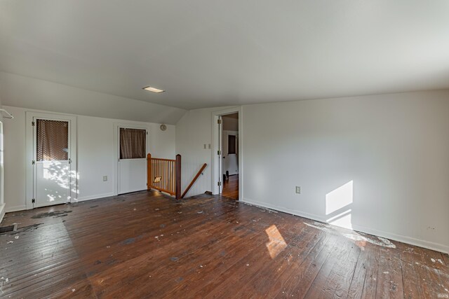 spare room featuring lofted ceiling and dark hardwood / wood-style flooring