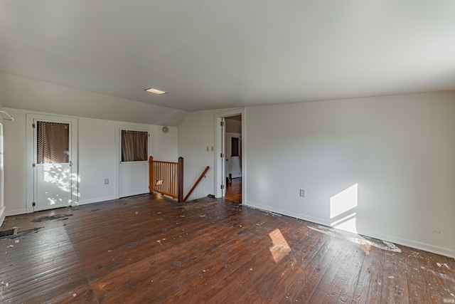 unfurnished living room featuring baseboards, vaulted ceiling, and hardwood / wood-style floors