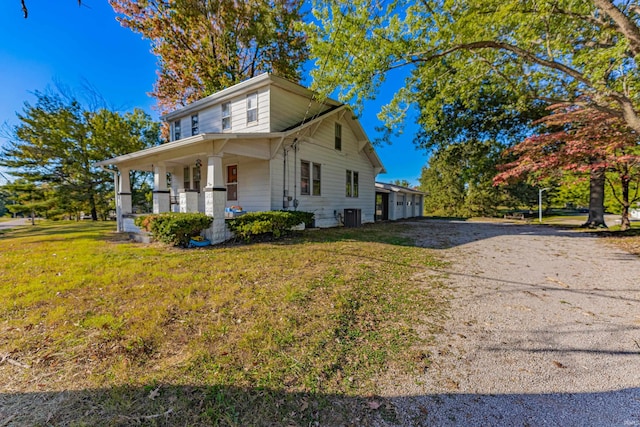 view of front of home featuring a porch, central AC, driveway, and a front yard