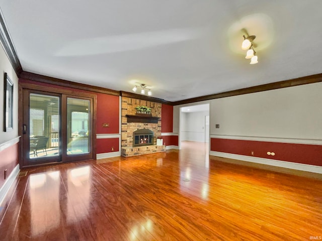 unfurnished living room featuring hardwood / wood-style flooring, ornamental molding, and a fireplace