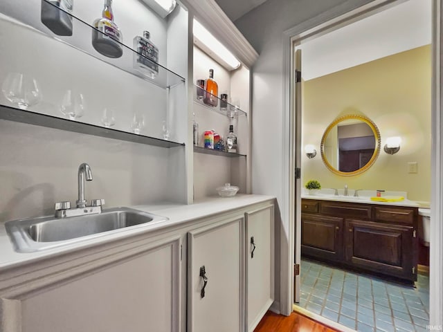 bar featuring light hardwood / wood-style floors, dark brown cabinetry, and sink