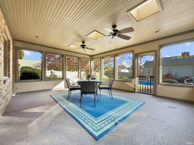 sunroom / solarium with a skylight, wood ceiling, a healthy amount of sunlight, and ceiling fan