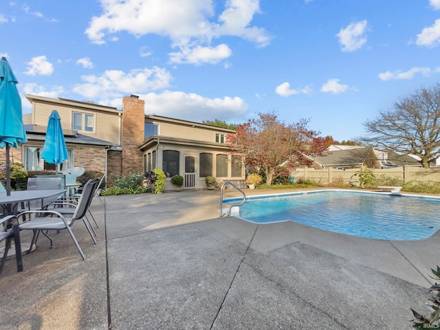 view of pool with a diving board and a patio